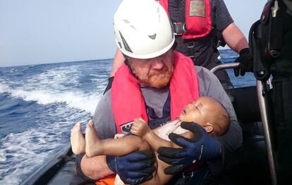 Un miembro de Sea-Watch sostiene a un bebé inmigrante en brazos.