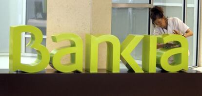 Una treballadora de la neteja treu la pols al logo de Bankia a la seu central de Bancaja.