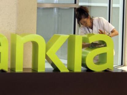 Una treballadora de la neteja treu la pols al logo de Bankia a la seu central de Bancaja.