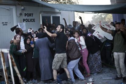 Los inmigrantes tratan de protegerse de las piedras en el puerto de Mitilene, en la isla griega de Lesbos