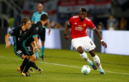 El jugador del Manchester United Paul Pogba trata de regatear a los jugadores del Real Madrid, Luka Modric y Dani Carvajal.