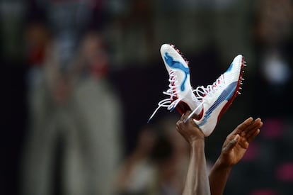 El jamaicano Usain Bolt levanta sus zapatillas tras ganar la final de 4x100 metros relevos.