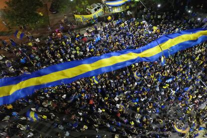 Hinchas del Boca Juniors se reúnen para despedir al equipo y despliegan la bandera del club.