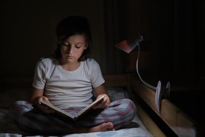 Boy reading in bed with reading lamp