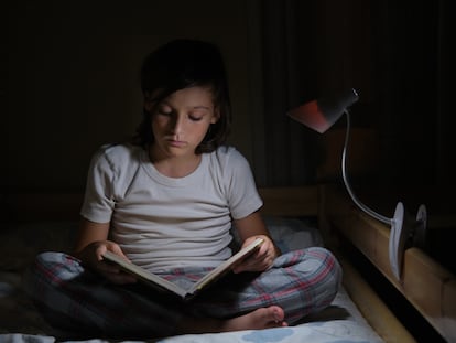 Boy reading in bed with reading lamp