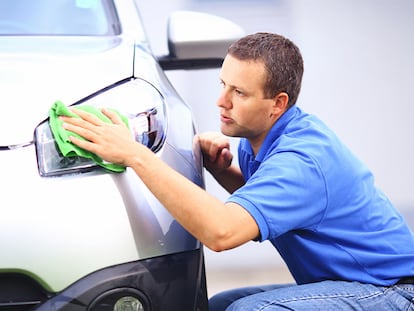 Un hombre puliendo los faros de su coche.