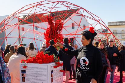 Una mujer recoge uno de los 5.500 claveles con los que se ha creado una instalación artística de flores para recordar el centenario de Lola Flores en Jerez de la Frontera.