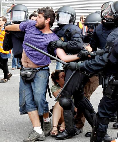 Varios <i>mossos</i> desalojan a un manifestante del movimiento 15-M en la plaza de Catalunya.