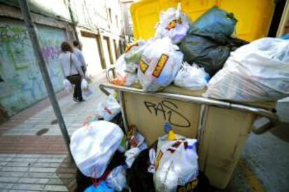Dos personas pasan junto a un contenedor repleto de basura, el pasado sábado en A Coruña.