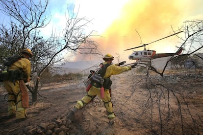 Bomberos despejan un área alrededor de un incendio forestal en un área montañosa del condado de San Bernardino.