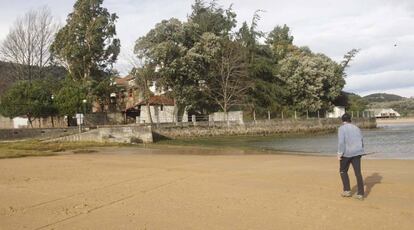 Un vecino pasea por la solitaria playa de Sukarrieta frente al edificio de las colonias de la BBK, reservado para el Guggenheim.