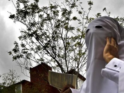 Un penitente de la Hermandad de La Paz espera a saber si saldr&aacute; su cofrad&iacute;a en estaci&oacute;n de penitencia, en Sevilla.