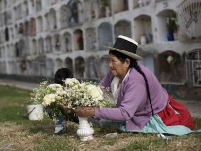 Una mujer adorna con flores la tumba de un familiar.