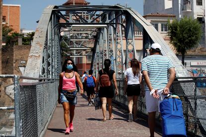 Unos vecinos cruzan el puente de la Torrassa, este sábado, en L'Hospitalet de Llobregat. EFE/Toni Albir