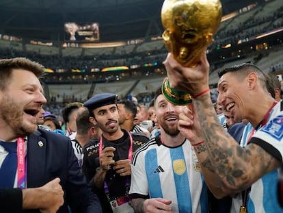 Ángel Di María muestra a Messi que la copa con la que acaba de celebrar el campeonato en Qatar es una imitación.