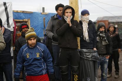 Migrants watch French officials tour  a makeshift camp set outside Calais, France, Tuesday Feb. 23, 2016. People fleeing conflict and poverty in Africa, the Mideast and Asia are facing an evening deadline to move out of the camp in the French port of Calais that has become a flashpoint in Europe's migrant crisis. (AP Photo/Jerome Delay)