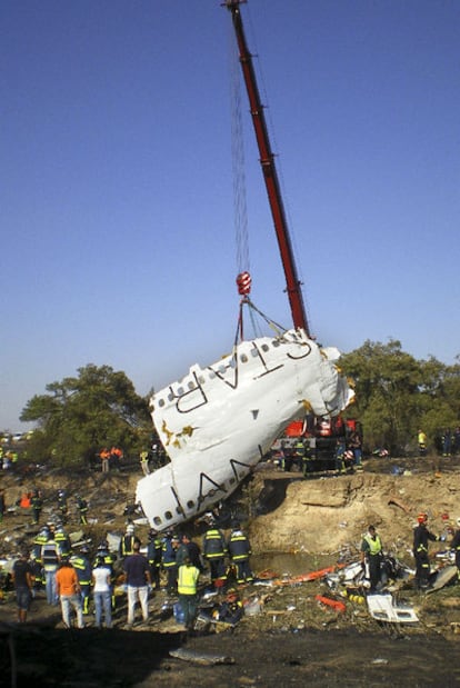 Una grúa levanta el fuselaje del avión de Spanair siniestrado.