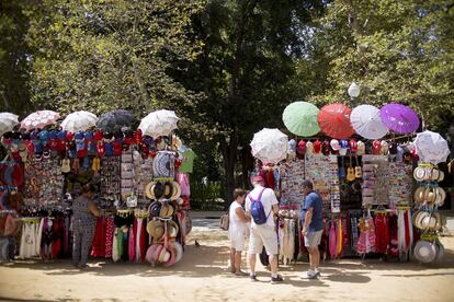 Varios turistas en un puesto de paraguas y sombreros cercanos a la Plaza de España (Sevilla).