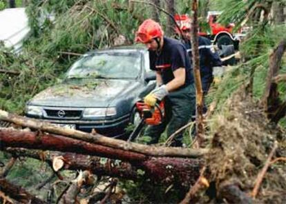 Los bomberos tratan de liberar un coche atrapado entre los árboles en un camping en Biscarosse, al suroeste de Francia.