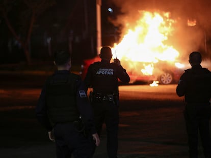 Agentes de policía frente a un auto incendiado por miembros del Cártel Jalisco Nueva Generación, en Zapopan, Estado de Jalisco (México), el 9 de agosto de 2022.