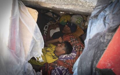 Dos migrantes duermen en el hueco de uno de los bloques de hormigón de la escollera.