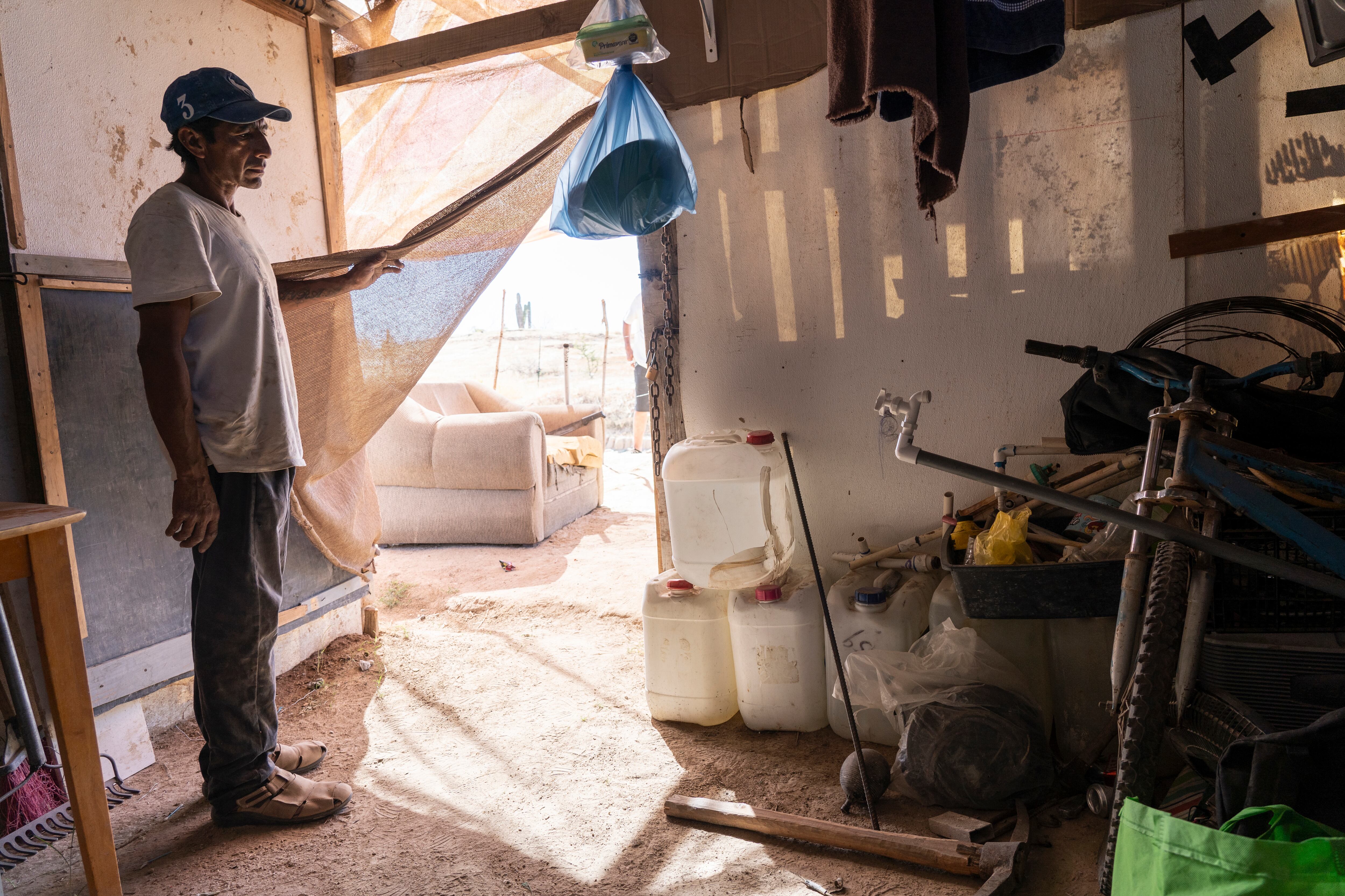 Alberto Jiménez muestra botellas donde almacena agua en una invasión de casas en Cabo San Lucas.