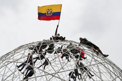 Un manifestante ondea una bandera encima de una escultura durante los enfrentamientos en las calles de Quito.