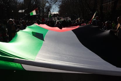 Varias personas sujetan una bandera gigante de Palestina durante la manifestación en contra de la guerra. 