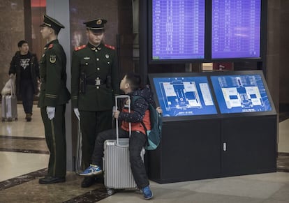 Un niño chino habla con un oficial de policía mientras espera su tren en la estación de Pekín.