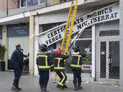Un grupo de bomberos retira el letrero de un centro médico en Barcelona