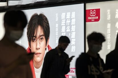 Varios ciudadanos chinos consultaban el día 10 sus móviles ante un anuncio de Alibaba para el Día del Soltero instalado en una estación de metro de Shanghái.