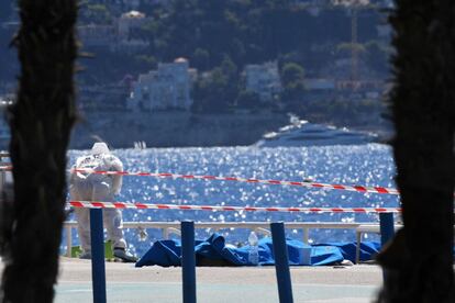 Un experto forense examina los cadáveres cubiertos con mantas de color azul en el paseo marítimo Promenade des Anglais, en la ciudad de Niza en Francia.
