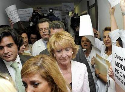 Aguirre y Güemes pasan junto a unas trabajadoras con carteles contra la privatización de la Sanidad pública.