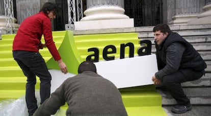 Un grupo de trabajadores coloca un cartel de AENA el miércoles, el día de salida a Bolsa.