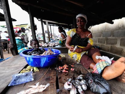 Una mujer limpia pescado en un mercado en Nigeria.