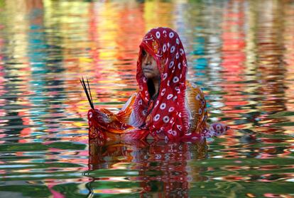 Uma mulher indiana adora o deus do Sol nas águas de um lago em Agartala (Índia). Durante o Chhath, são realizados rituais para agradecer a Suria, deus do Sol, a manutenção da vida na terra.