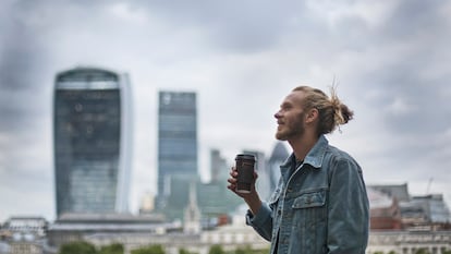 Un hombre tomando un café por la ciudad llevando su chaqueta vaquera