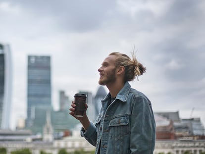 Un hombre tomando un café por la ciudad llevando su chaqueta vaquera