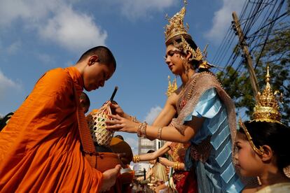 En la celebración, tradición y fiesta van de la mano. Con los primeros rayos de sol de cada 13 de abril, los budistas más devotos se acercan a los templos para recitar oraciones y realizar ofrendas a los monjes para conseguir buena suerte para el año entrante. En la imagen, una mujer vestida con el traje tradicional de Tailandia da una ofrenda a un monje budista en Bangkok.