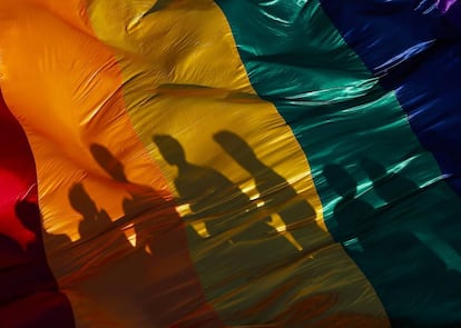 La sombra de unos participantes en una marcha del Orgullo LGTBQ en Managua se refleja sobre la bandera del arco iris, símbolo de la causa.