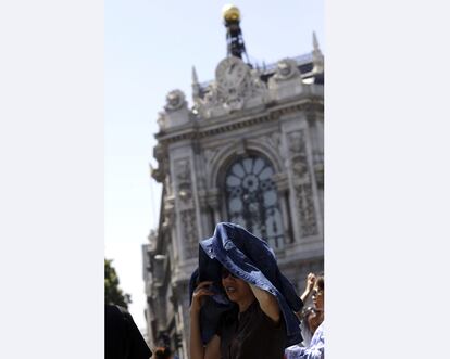 Tras los ascensos del lunes y el martes, los termómetros suben todavía más este miércoles en casi toda España, lo que será notable en el valle medio del Ebro, áreas de Barcelona y Girona, y el sur de Valencia y el norte de Alicante. En la imagen, turistas que visitan la capital se protegen del sol.