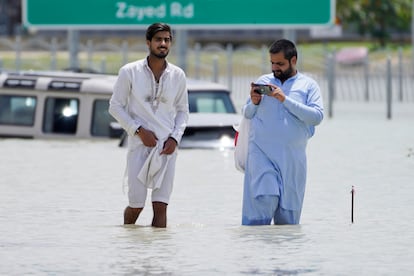 Dos hombres caminan por una carretera inundada en Dubái, este miércoles. 