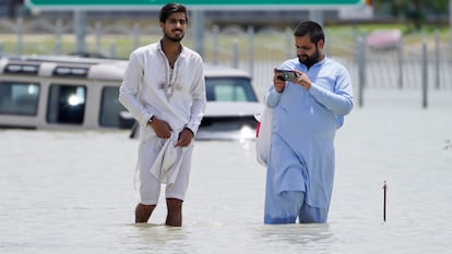 Two men walk through floodwater in Dubai, United Arab Emirates, Wednesday, April 17, 2024. The desert nation of the United Arab Emirates attempted to dry out Wednesday from the heaviest rain ever recorded there after a deluge flooded out Dubai International Airport, disrupting the world's busiest airfield for international travel. (AP Photo/Jon Gambrell)