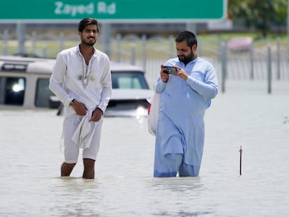 Two men walk through floodwater in Dubai, United Arab Emirates, Wednesday, April 17, 2024. The desert nation of the United Arab Emirates attempted to dry out Wednesday from the heaviest rain ever recorded there after a deluge flooded out Dubai International Airport, disrupting the world's busiest airfield for international travel. (AP Photo/Jon Gambrell)