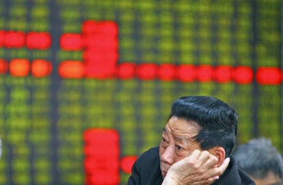 Un inversor frente a los paneles de la Bolsa en Shangh&aacute;i (China)