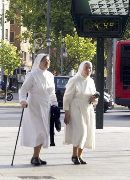 Dos monjas pasan por delante de un termómetro en Zaragoza.
