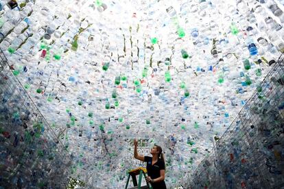Una empleada coloca una botella de plástico en la escultura 'Derroche de espacio' hecha con botellas recicladas, en el zoológico de Londres (Reino Unido).
