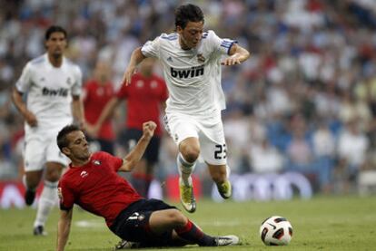 Özil se lleva el balón encimado por Camuñas.