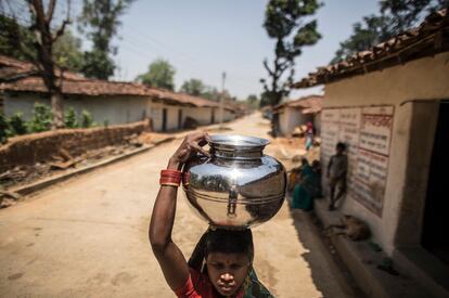 Una madre lleva agua para cocinar al centro de día de niños y embarazadas de Maheshpur, en la región india de Chhattisgarh.
