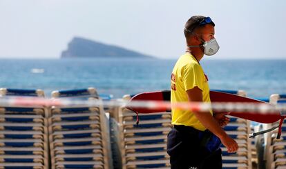 Un socorrista camina con máscara por la playa de Levante de Benidorm (Alicante), cerrada al público.